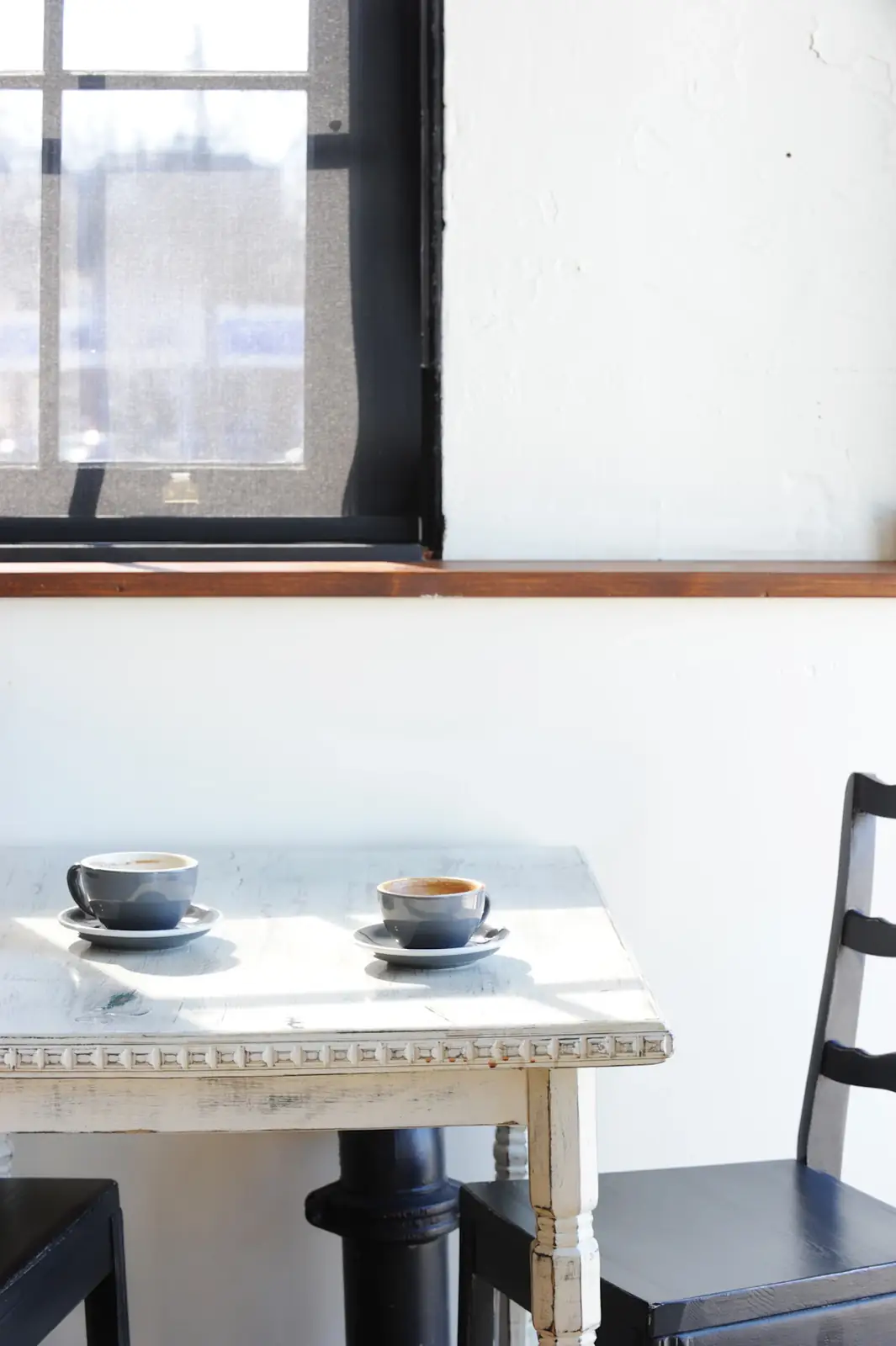 Mesa junto a la ventana con un café y un cuaderno abierto, iluminada por la luz de la mañana